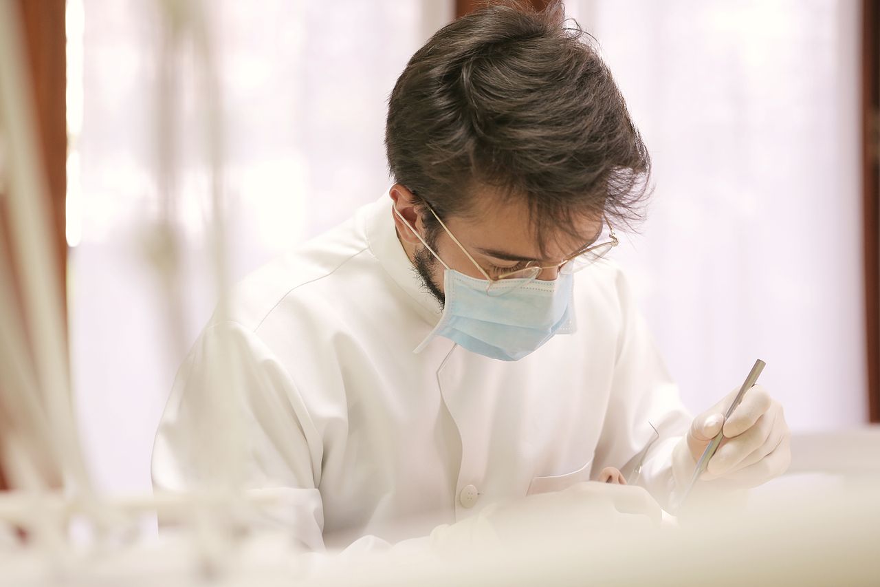 Dentist in protective gear performing dental treatment, showcasing the precision and professionalism of dental care.